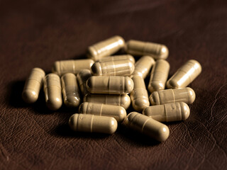 Pile of beige capsules scattered on textured brown surface, suggesting health, wellness, and natural remedies