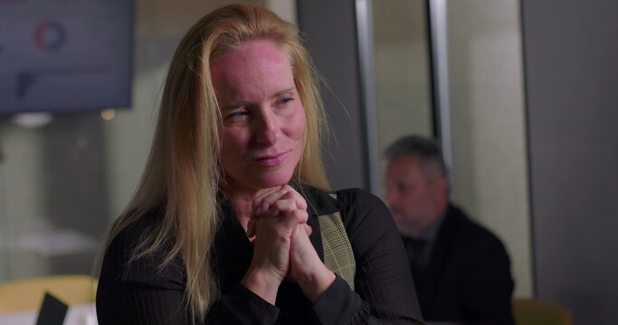 Blonde businesswoman clenching jaw in visible frustration during office meeting, overwhelmed and tense as workplace stress reaches breaking point