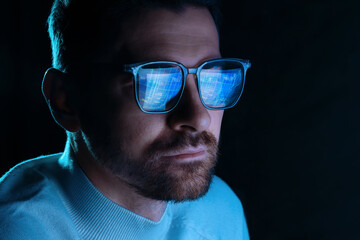 Man wearing glasses with reflection on black background, closeup. Space for text