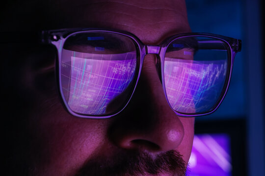Man wearing glasses with reflection in dark room, closeup