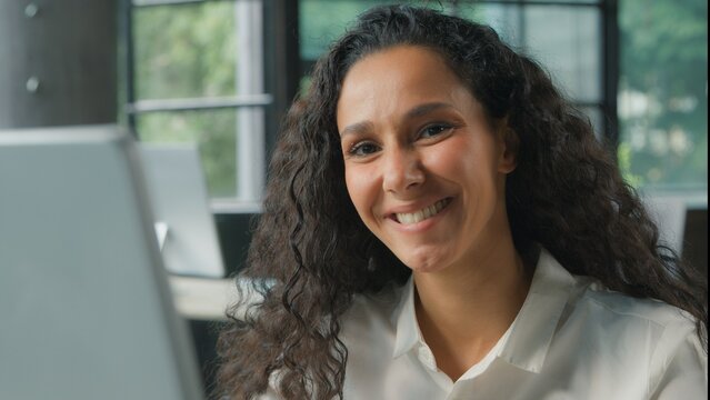 Indian business woman Hispanic female Arabian ethnic businesswoman working on computer in office looking at camera smiling happy positive lady executive worker entrepreneur manager work online at desk