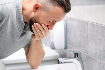 Fototapeta premium Man suffering from nausea over sink in bathroom