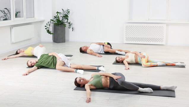 Group of people doing stretching exercise on fitness mats in gym - Powered by Adobe