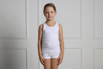 Little girl in underwear near light wall
