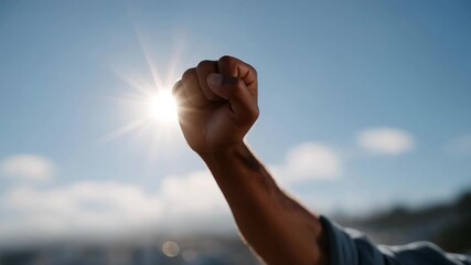 Silhouette of raised arm backlit by sun rays — symbolizing empowerment, optimism, achieving goals, and motivational imagery for wellness and personal development content. cinematic color