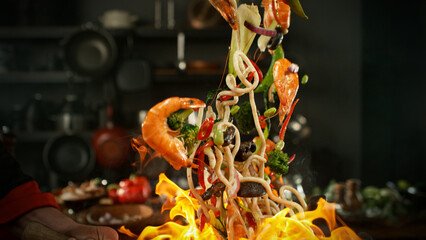 Naklejka premium Freeze Motion of Flying Asian Meal with Vegetable and Prawns into Wok Pan