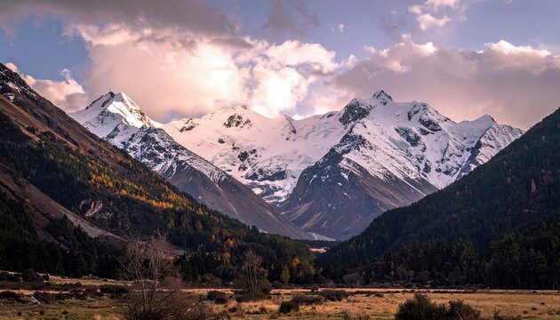 A dramatic landscape featuring snow-covered mountain peaks, a valley with autumn foliage, and dark pine forests under a cloudy sky.