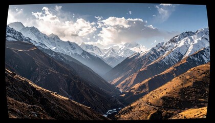 A vast mountain range with snow-covered peaks and rugged, sunlit slopes, leading down to a deep valley with a winding river.