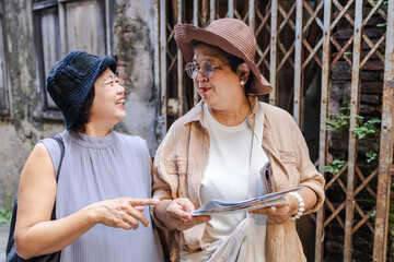 Two senior travelers laugh warmly in a city tour with old school way navigation map, elderly women celebrate retirement, explore new activities together, aging society lifestyle, pension healthcare