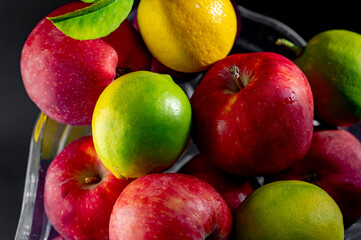 Still Life with Red Apples and Lemons in a Glass Vase on Black Background