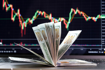 Stacks of hundred-dollar bills against a crypto exchange chart.