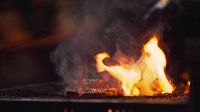 Slow motion showing closeup of a torch flame heating a grill plate at a night yatai food stall in Fukuoka, Japan, with sparks, smoke, and glowing light effects