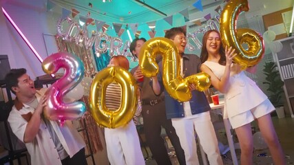 Asian business team celebrating New Year 2026 or major milestone achievement in office party,holding large 2026 foil number balloons and confetti falling.Concept of corporate success,festive teamwork
