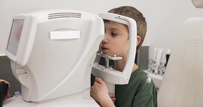 Closeup cute boy undergoing automated vision examination with autorefractor machine