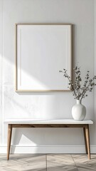 Blank picture frame on white wall with wooden bench and vase.