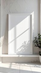 Blank white canvas frame mockup with sunlight and plant shadow.