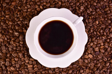 A cup of strong coffee against the background of coffee beans. Flat lay.
