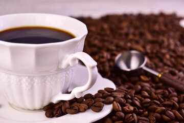 A cup of strong coffee against a background of coffee beans.

