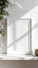 Blank white frame on a shelf with green leaves and natural sunlight.