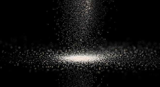 Abstract shower of tiny white particles falling downward onto a brightly lit surface