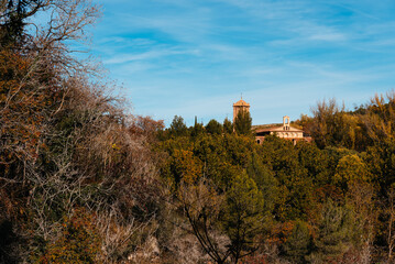Naklejka premium Ancient monastery nestled in autumn forest landscape under blue sky. Monasterio de Piedra
