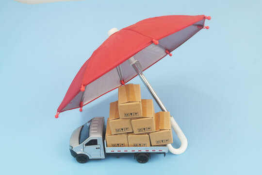 Lorry truck with many boxes under red umbrella on blue background. Protection and insurance for freight transportation concept	