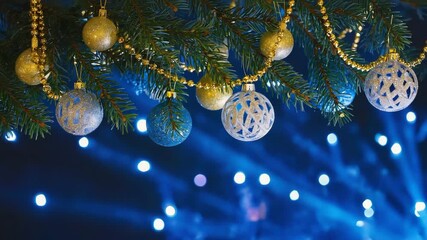 A festive close-up video of golden Christmas ornaments hanging on a fir tree branch, set against a vibrant blue bokeh background. The sparkling decorations and soft glowing lights create a warm and el - Powered by Adobe