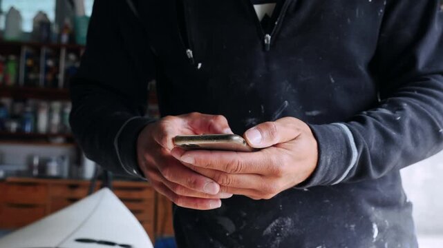 Crafting surfboards and connecting on smartphone in shaper workshop