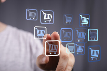 Person's finger interacting with online shopping cart icons. E-commerce concept, digital purchase and retail. Buying online, selecting items.