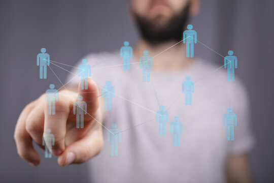 Man's finger interacts with a digital network of virtual human icons, symbolizing connection and networking in the digital world. Shows teamwork