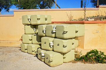 A stack of beige modular pontoon float blocks for building floating marine platforms, stacked outdoors by a wall under bright sun.