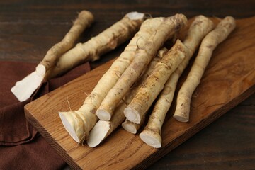 Fresh raw horseradish roots on wooden table, closeup