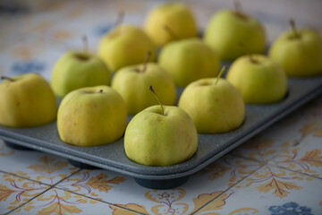 Yellow apples organised in a baking mould, suitable for advertisements, recipe websites, nutrition projects and promotional materials for kitchenware brands.