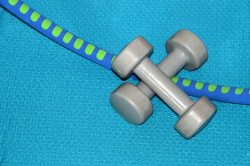Two dumbbells and a hula hoop close-up on a blue gym mat