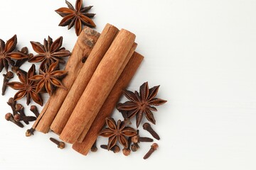 Different spices (cinnamon, cloves and anise) for mulled wine on white wooden table, top view. Space for text