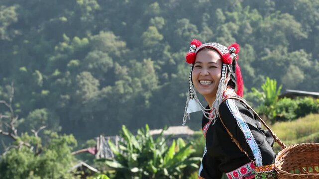 Smiling ethnic woman in traditional tribal dress gesturing with hand in rural village, showing cultural pride, hospitality, and joyful lifestyle in scenic nature