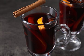 Tasty mulled wine in glass mugs on grey table, closeup