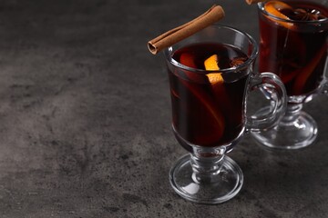 Tasty mulled wine in glass mugs on grey table, closeup. Space for text