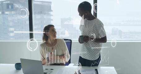 Discussing team reviewing laptop and charts at office windows with AR overlays, in business attire