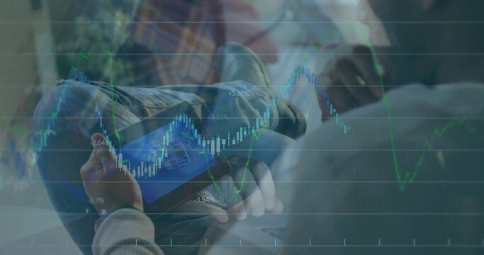 Holding man studying tablet in lounge wearing casual clothes with laptop and candlestick charts