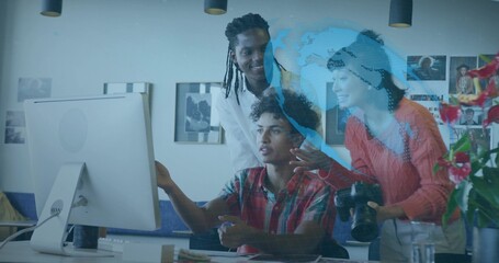 Collaborating seated man in red plaid shirt editing on desktop computer at studio, with DSLR camera