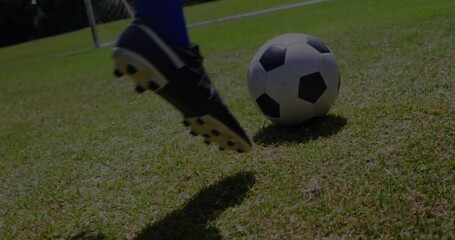 Obraz premium Kicking player swinging black cleat and blue sock at b and w ball on grass, goalpost, copy space