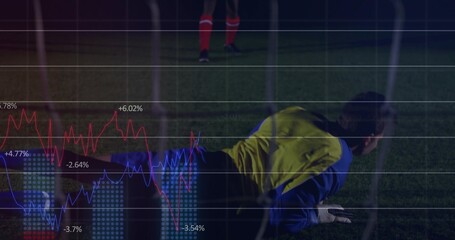 Diving keeper wearing yellow bib gloves sliding on night pitch with net red socks financial charts