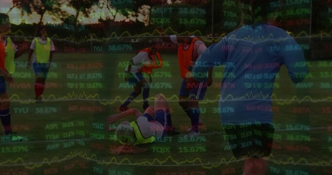 Lying player in neon bib drawing attention from team on grassy soccer pitch, stock charts overlay
