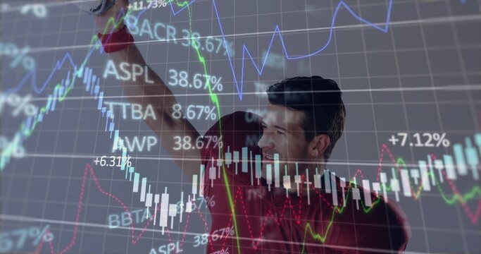 Pointing man in red shirt gesturing to market screen in office showing candlesticks, percent labels