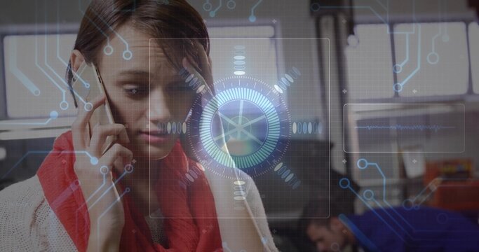 Talking on smartphone, woman wearing red scarf and knit sweater in office with monitors, holo HUD