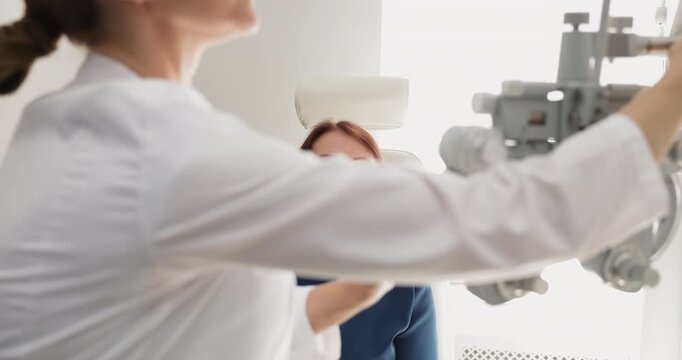 Optometrist adjusting phoropter during eye examination for older patient, closeup