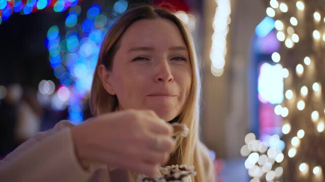 woman taking playful messy bite from milkshake under neon holiday lights, visitor at lively street fair