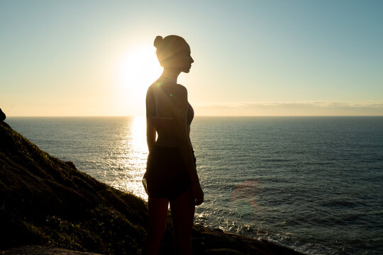 Young woman in sportswear watching the sunset by the sea