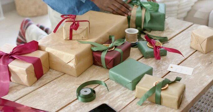 Spotting blank tags, diverse couple wrapping, sealing gift boxes at home for gifting with phone